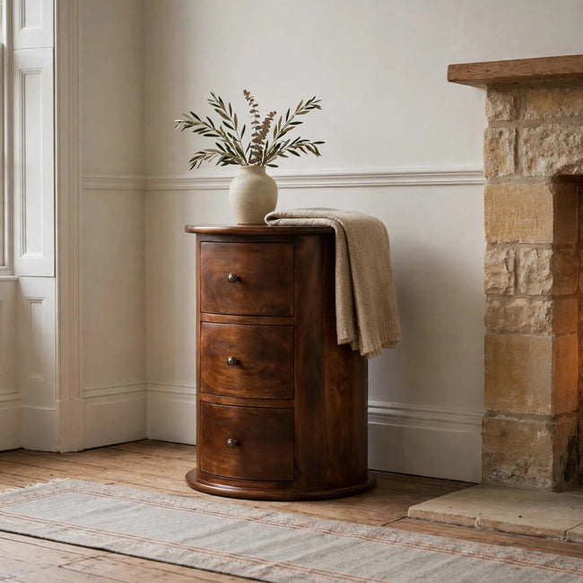 Chestnut drum chest with three drawers and shiny knobs styled as a bedside table