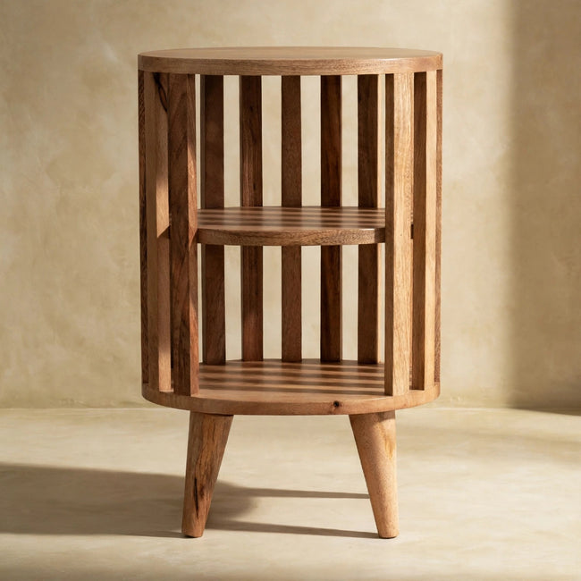 Ariella wooden bedside table with a lamp on top beside a bed