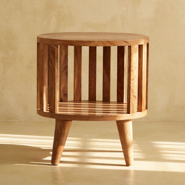 Ariella mango wood bedside table with an open shelf and oak-ish finish beside a bed