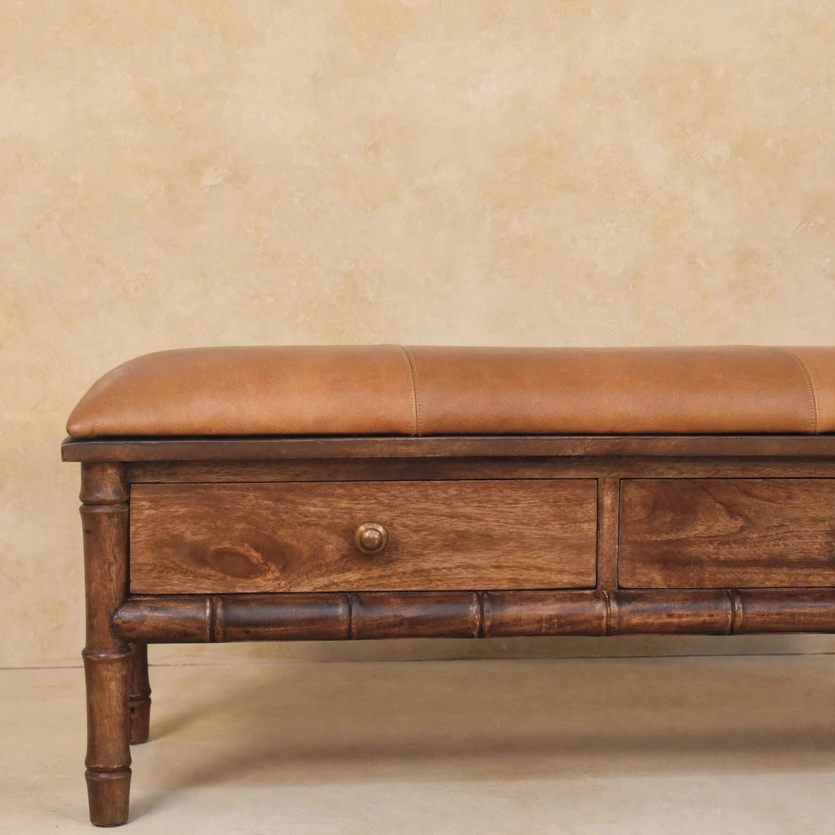 Mango wood bench with a mocha leather cushion and a lower shelf holding décor