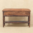 Close view of the carved front of a mango wood bench with a mocha leather cushion in a home interior