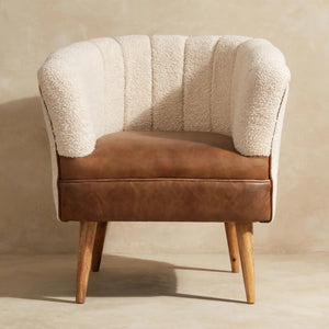 Front view of a cream boucle armchair with a buffalo hide leather seat and wooden legs