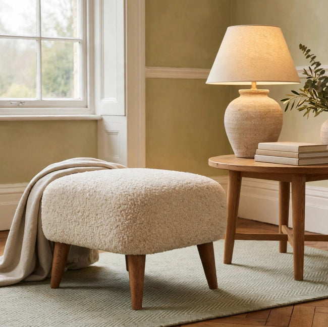 Cream boucle square footstool with solid mango wood legs in a living room