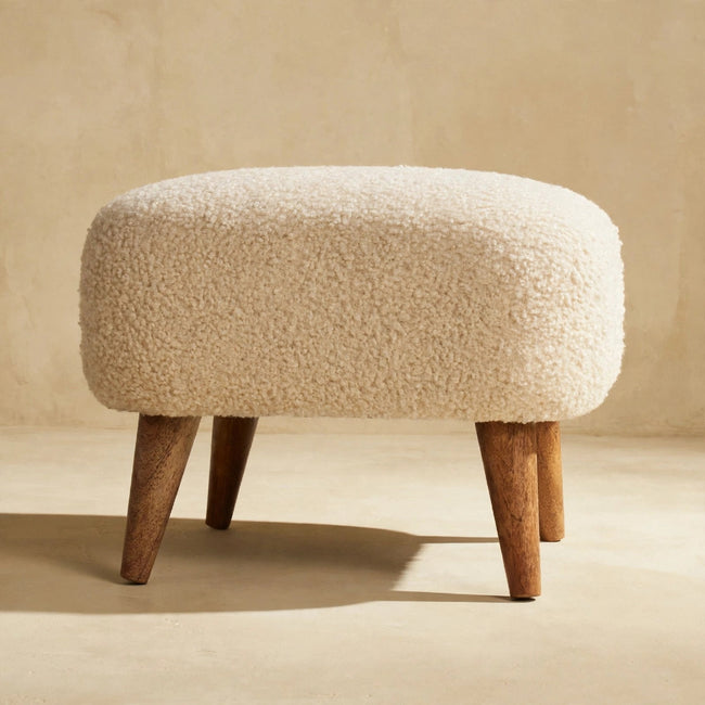 Side view of the square cream boucle footstool showing its mango wood legs