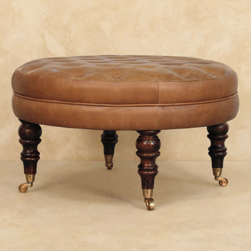Brown tufted leather round ottoman used as a footrest beside a sofa