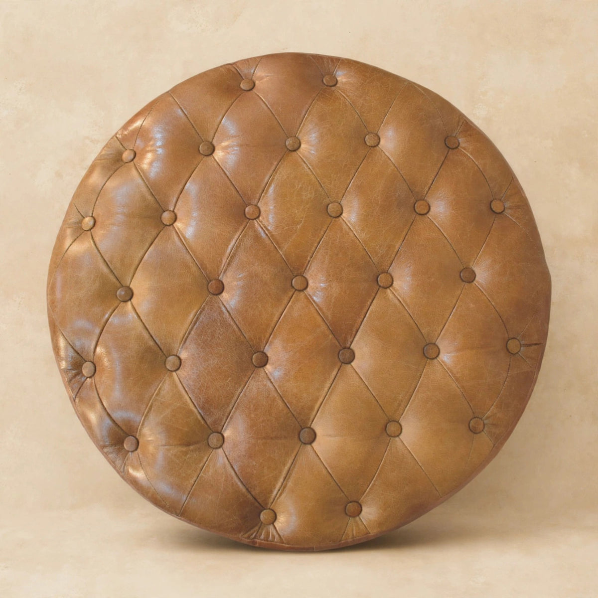 Round tufted leather ottoman with caster legs near an entryway