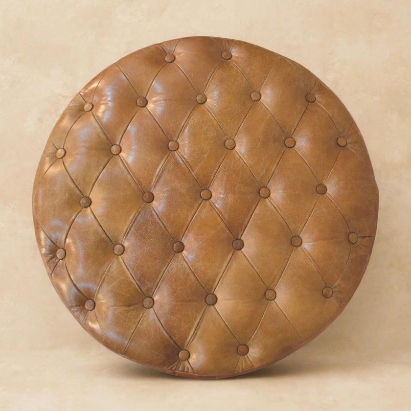 Round tufted leather ottoman with caster legs near an entryway