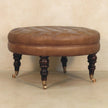 Close view of brown buffalo leather ottoman with deep button tufting in a styled interior