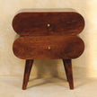 Chestnut mango wood bedside table with brass drawer knobs beside a bed
