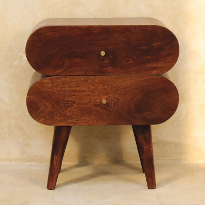 Chestnut mango wood bedside table with brass drawer knobs beside a bed
