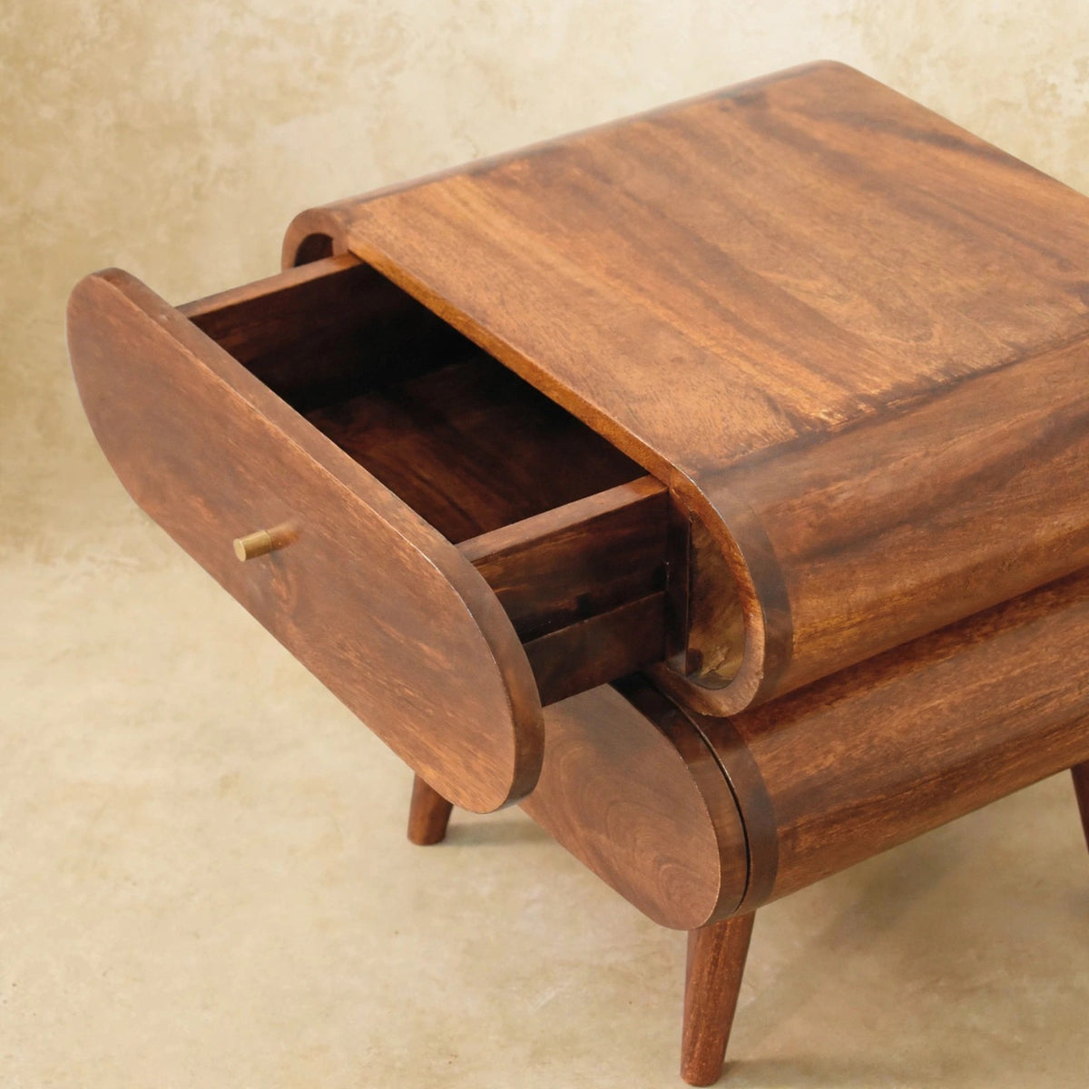 Close view of the round drawer front and brass knob on the chestnut bedside table
