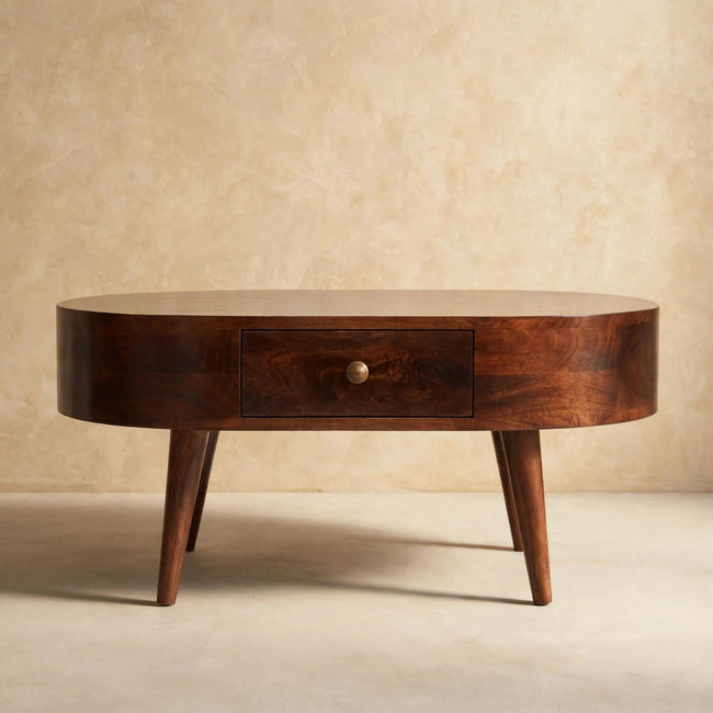 Walnut-finish rounded coffee table with two drawers and shiny knobs, styled in a room