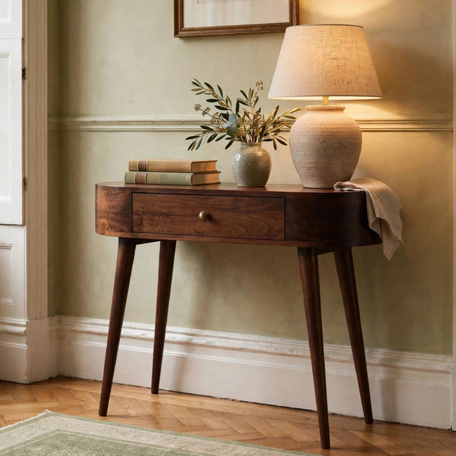 Small rounded walnut finish console table with one drawer in a room setting