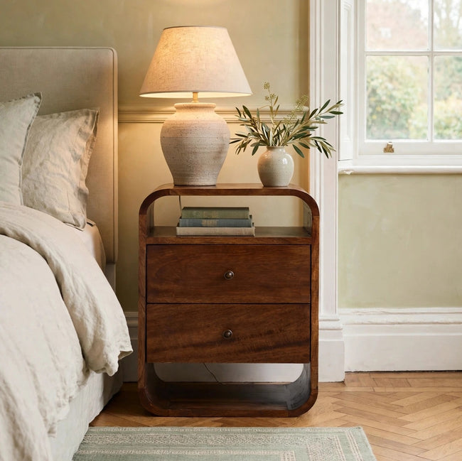 Chestnut Curve 2 drawer bedside table in solid mango wood, shown in a bedroom setting