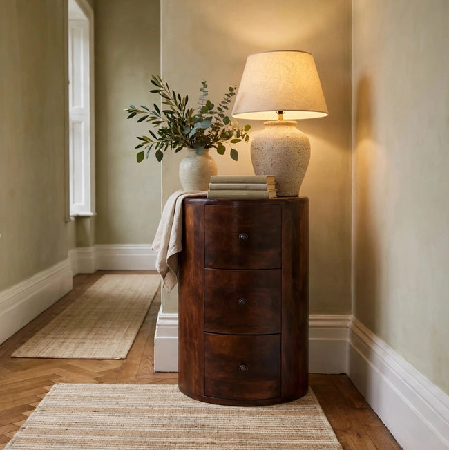 Round chestnut drum chest with three drawers and shiny knobs in a room setting