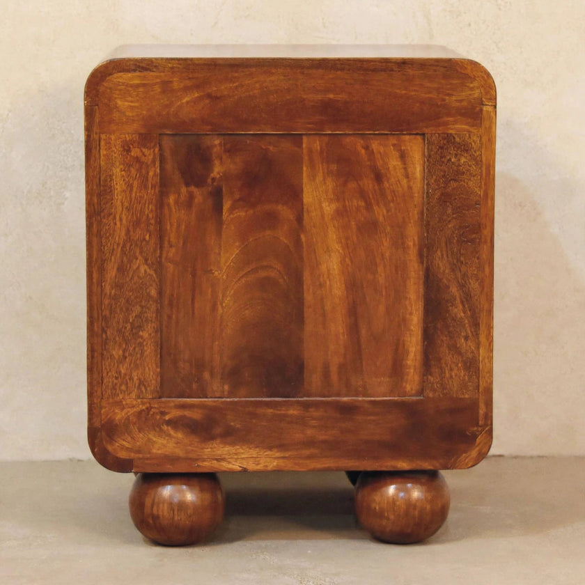 Woven bedside table with shiny drawer knob in a bedroom setting