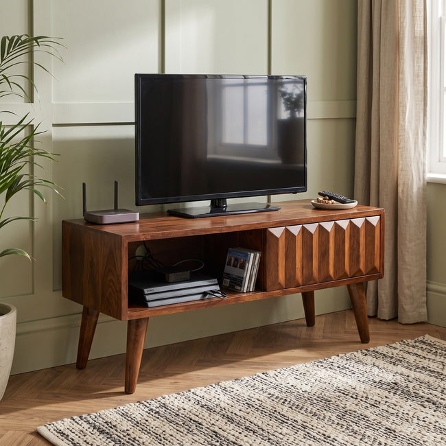 Chestnut mango wood media unit with a prism-carved sliding door, shown in a living room