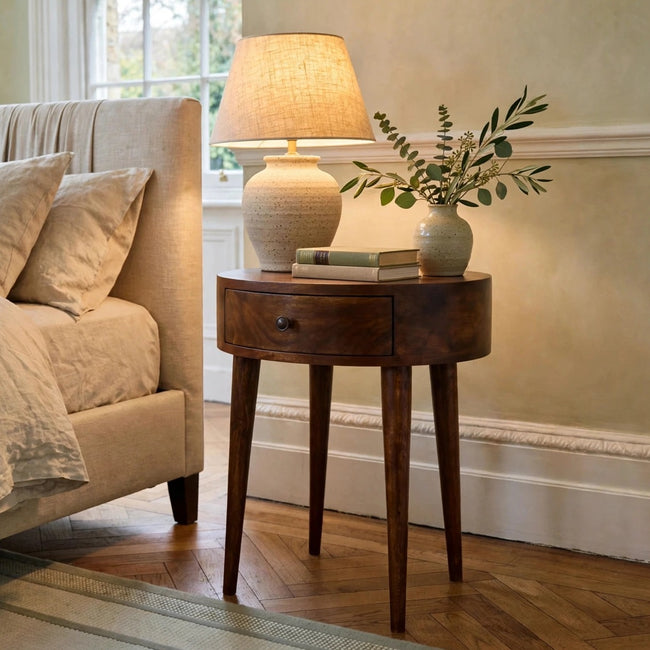 Chestnut semi circle bedside table in solid mango wood, shown in a bedroom setting