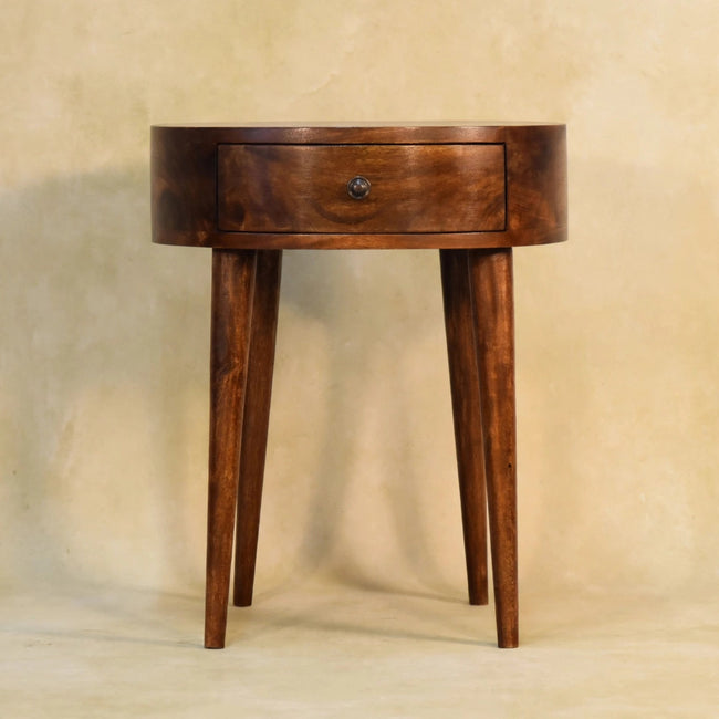 Semi circle bedside table with a chestnut finish and metal drawer knob, styled in a room
