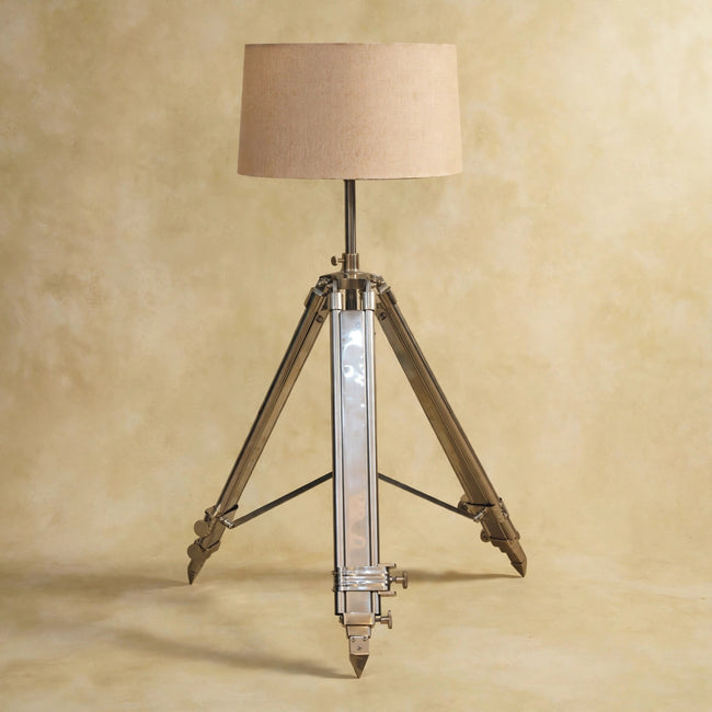 Front view of the chrome tripod lamp with its neutral shade in a room