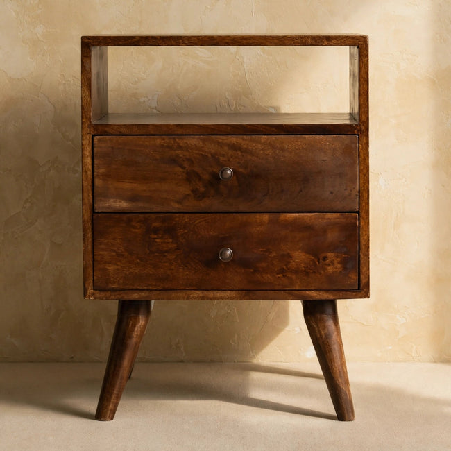 Chestnut mango wood bedside table with Nordic-style legs standing beside a bed
