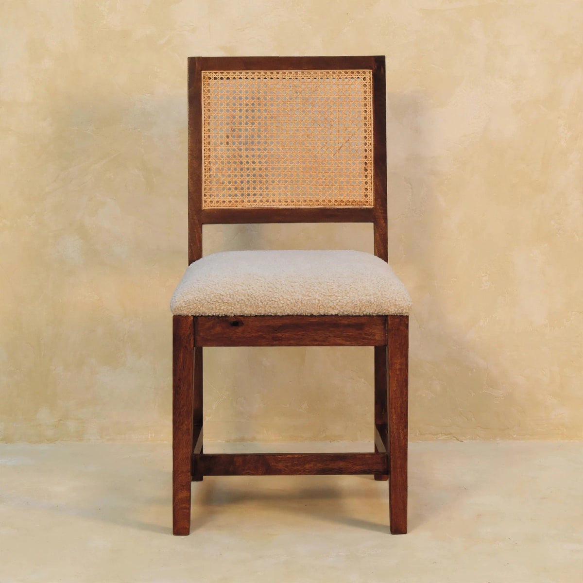 Front view of the cream boucle accent chair with a rattan back in a room setting