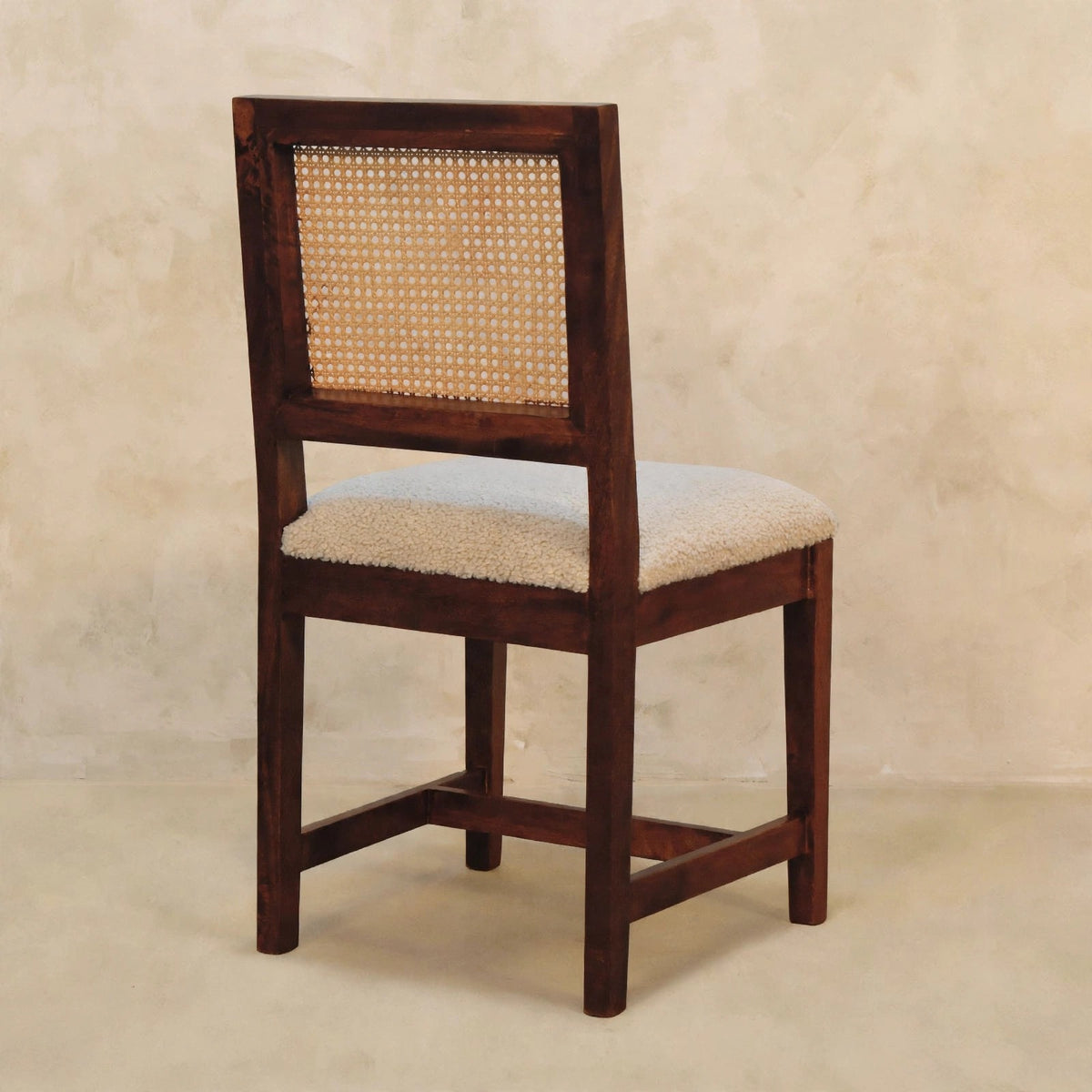 Close-up of the chestnut finish mango wood leg and frame on the cream boucle chair