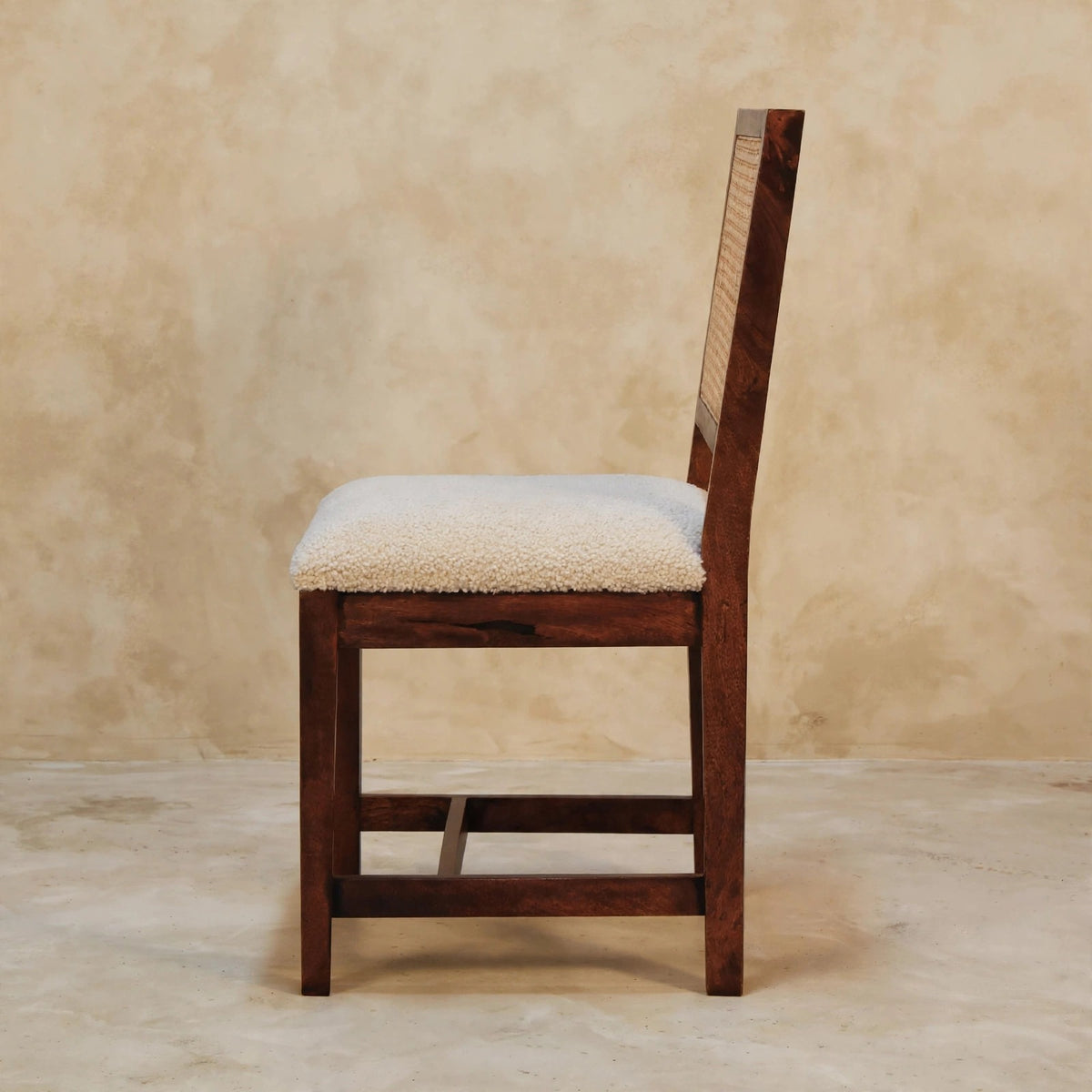 Close-up of the woven rattan back on the cream boucle accent chair
