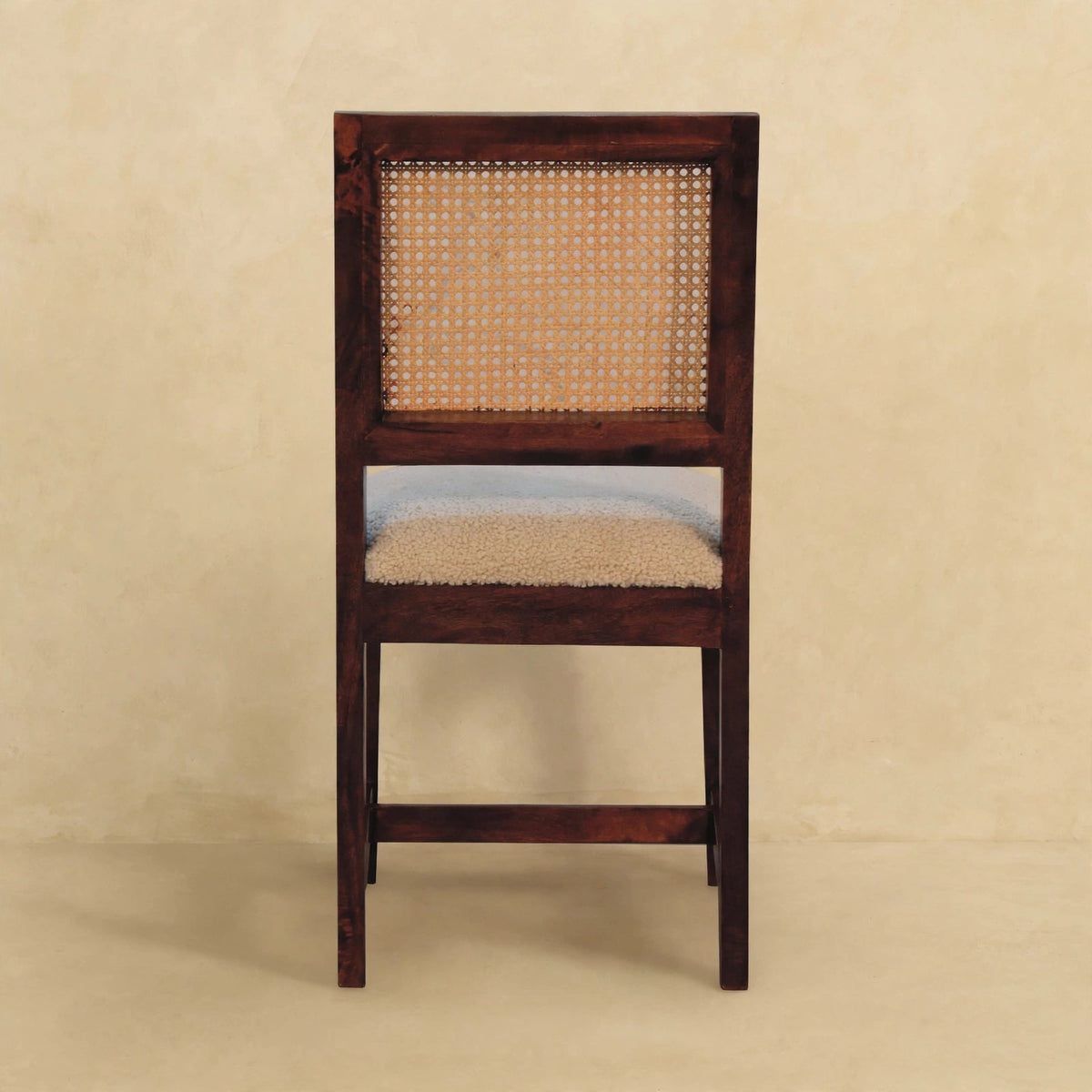 Cream boucle rattan chair seen at an angle, showing the seat and wood frame