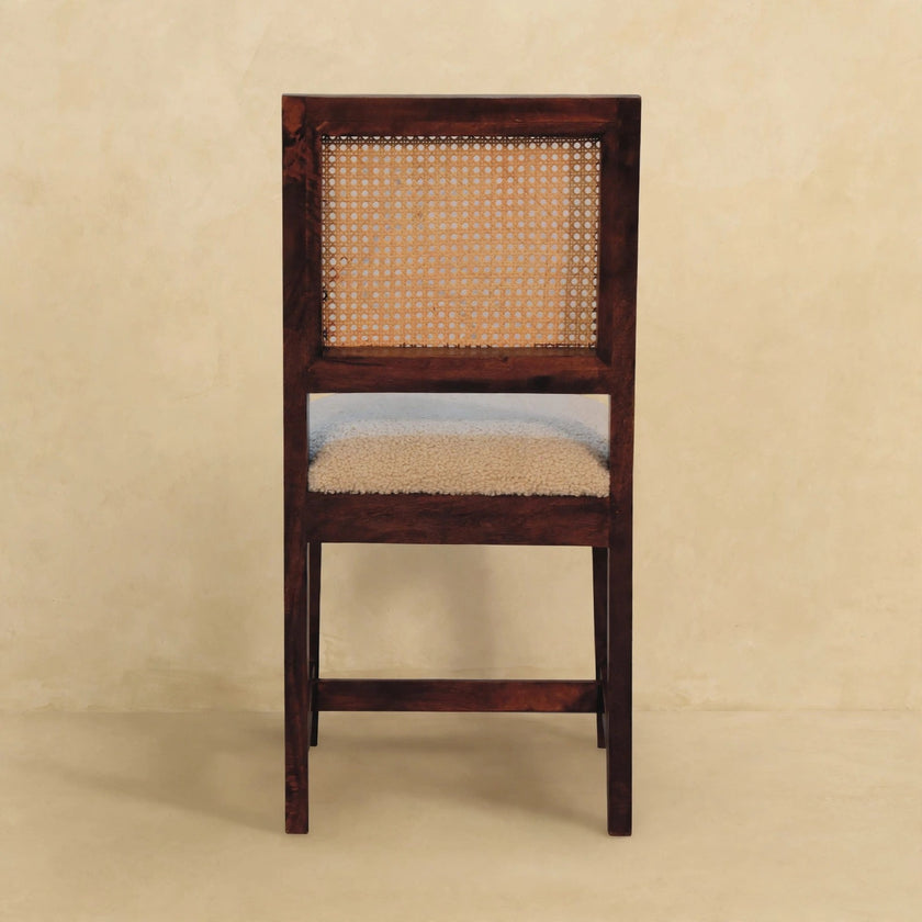 Cream boucle rattan chair seen at an angle, showing the seat and wood frame