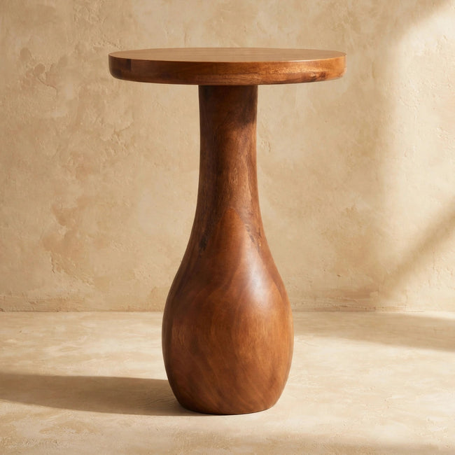 Round-top wooden side table with a curved pedestal base next to a sofa