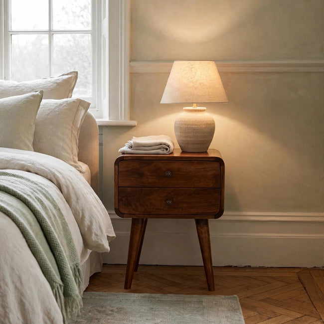 Curved chestnut bedside table in solid mango wood styled in a bedroom