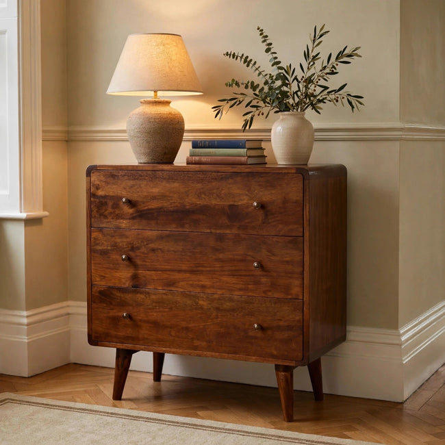 Curved chestnut chest of drawers in solid mango wood styled in a bedroom
