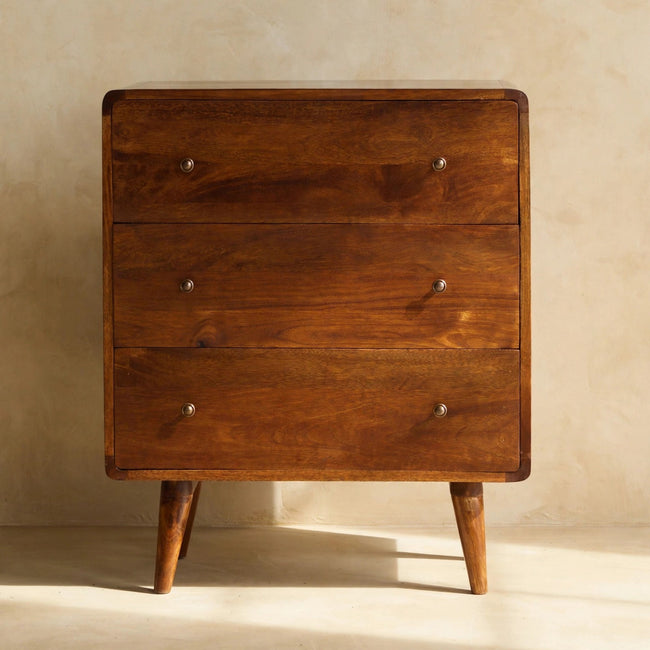 Chestnut mango wood chest with curved corners and shiny drawer knobs in a room setting