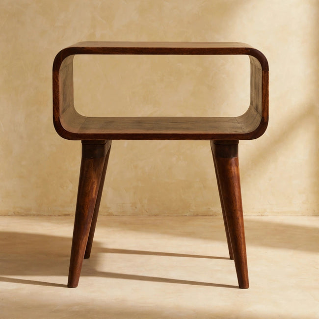 Chestnut bedside table on four Nordic style legs standing beside a bed