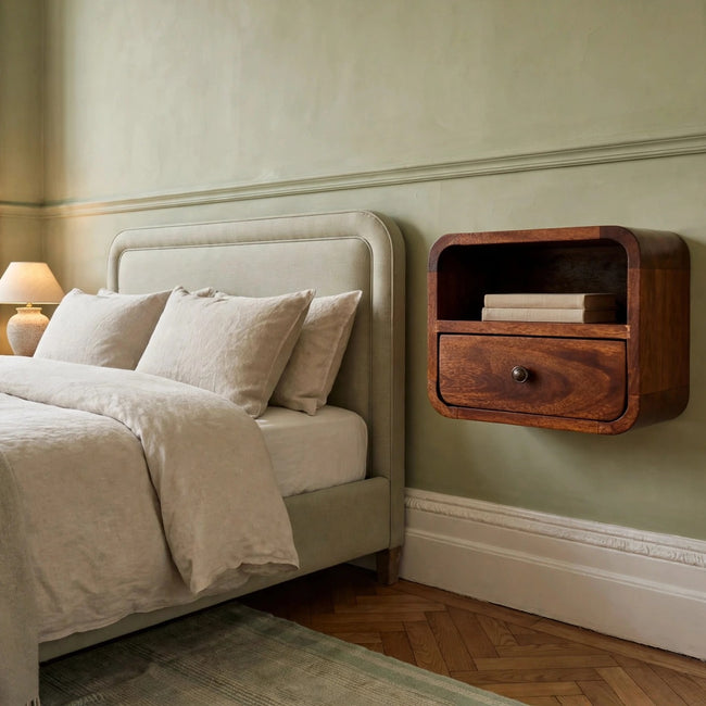 Small wall mounted chestnut bedside table with curved edges in a bedroom