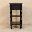 Angled view of the turned legs and open shelves of the carbon ash side table