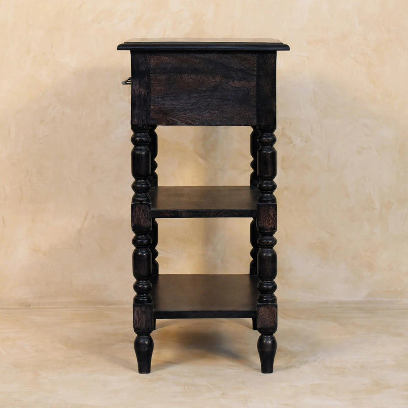 Angled view of the turned legs and open shelves of the carbon ash side table