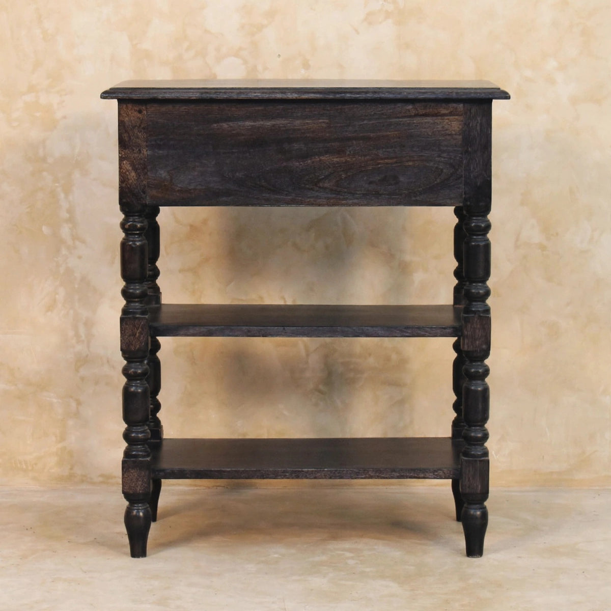 Turned-leg mango wood side table in a styled living room next to a sofa
