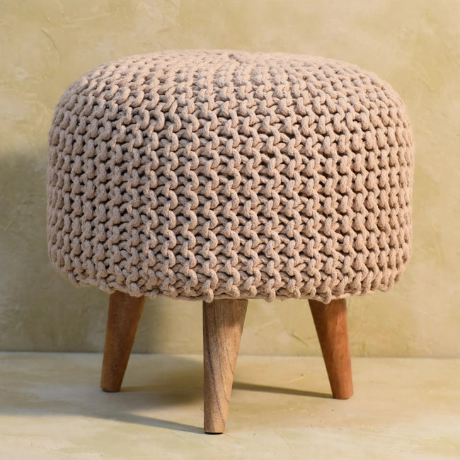 Round beige woven footstool beside a sofa, used as a footrest