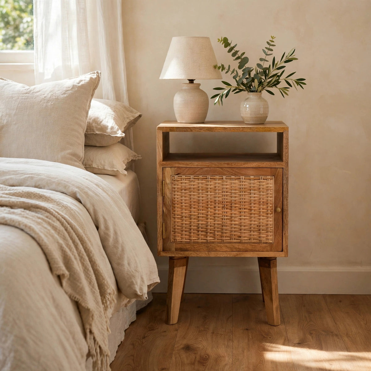 Knit Door Bedside table with a rattan door front and wooden legs in a bedroom setting