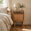 Knit Door Bedside table with a rattan door front and wooden legs in a bedroom setting
