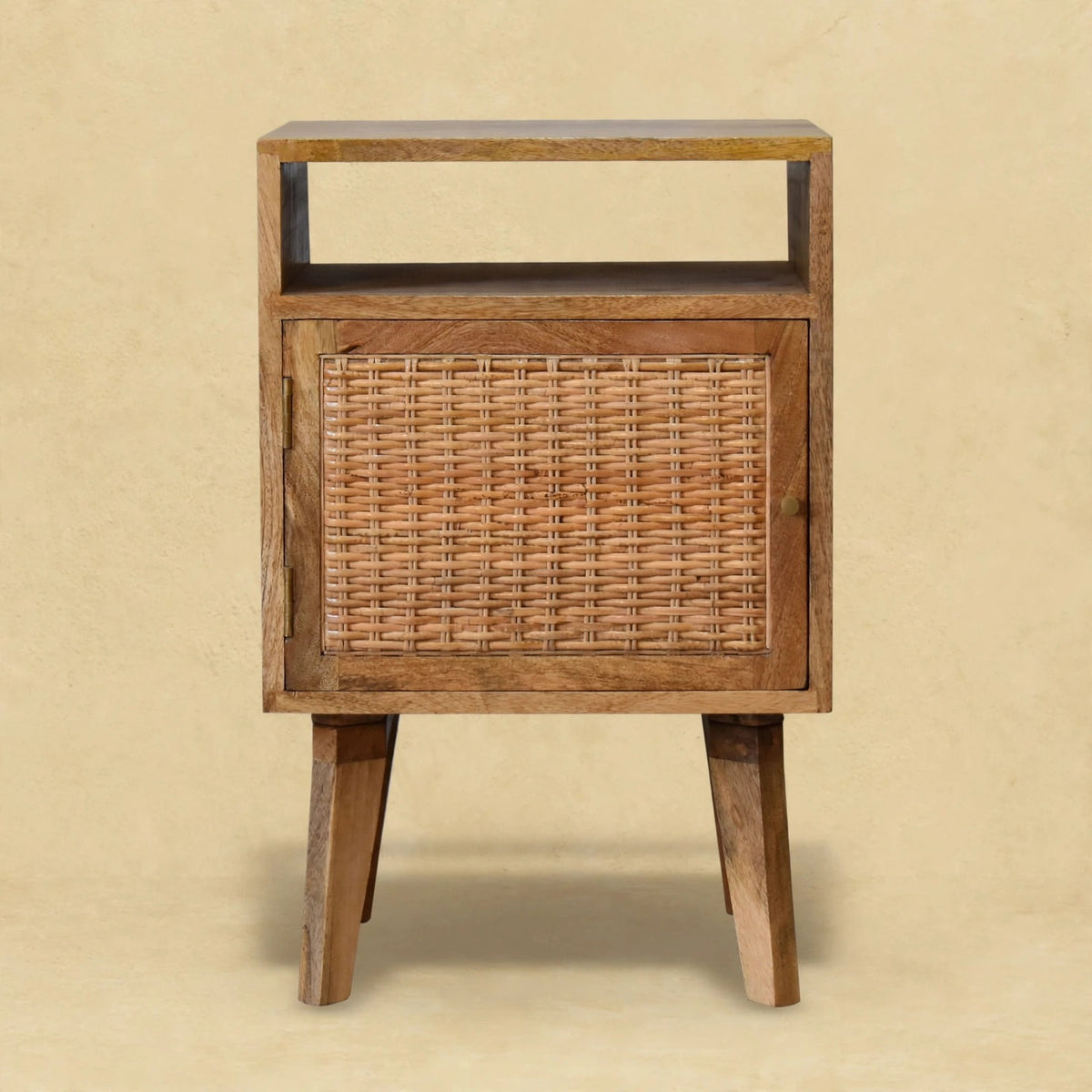 Mango wood bedside table with a rattan door standing beside a bed in a styled room