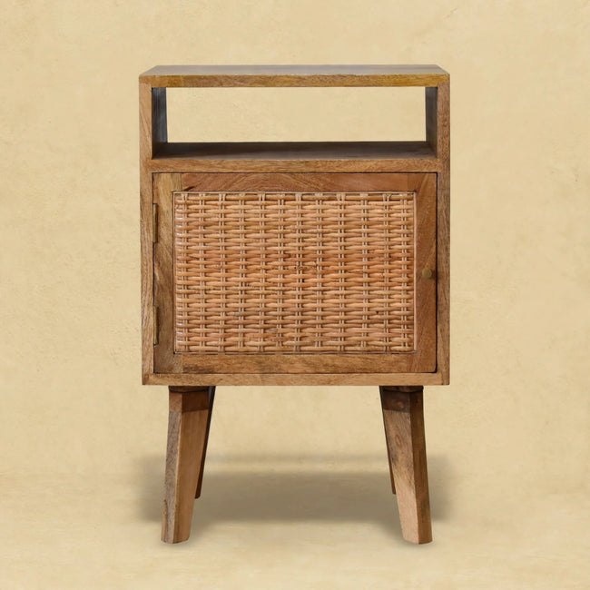 Mango wood bedside table with a rattan door standing beside a bed in a styled room