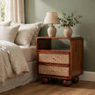 Chestnut mango wood 2 drawer nightstand with rattan drawer fronts beside a bed