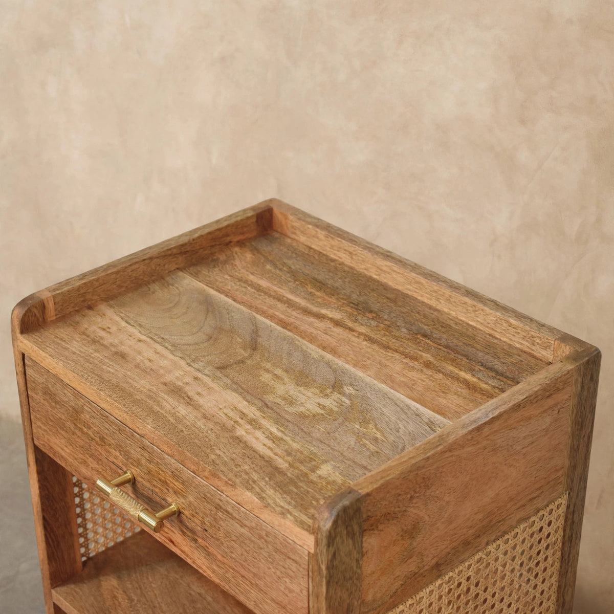 Angled view of the bedside table showing the drawer and open storage in a bedroom
