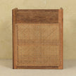 T-bar open bedside table next to a bed, showing the wood grain