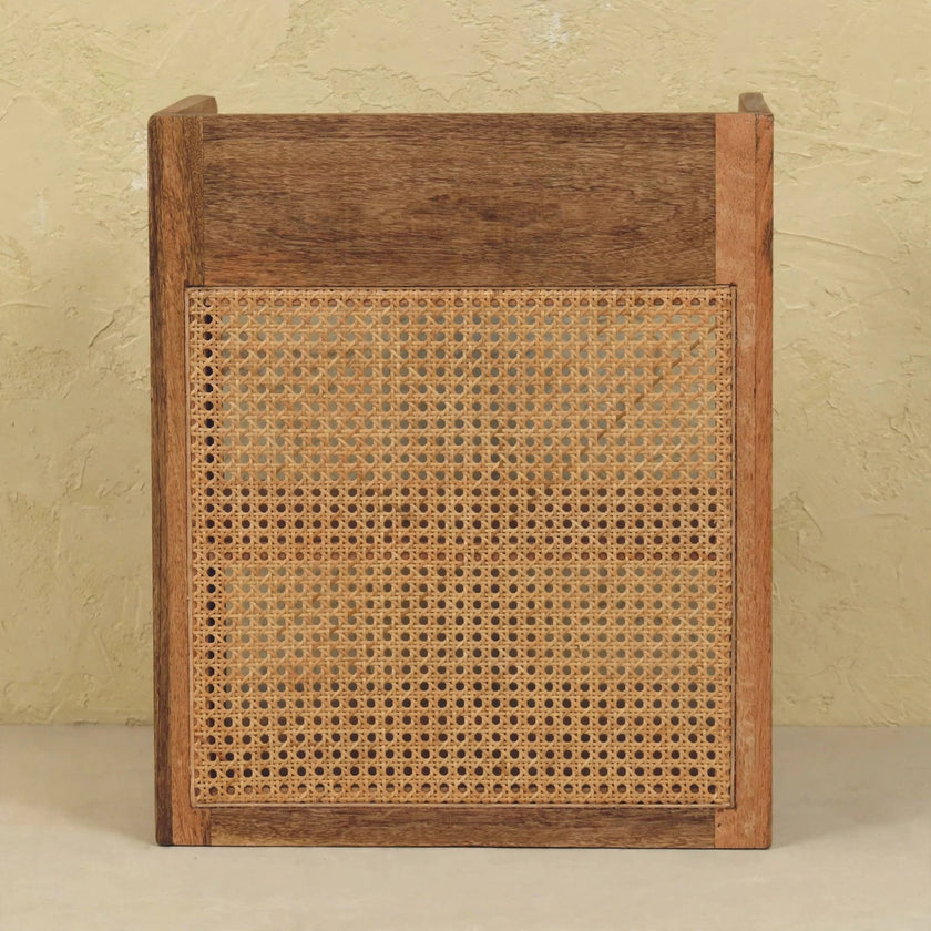 T-bar open bedside table next to a bed, showing the wood grain