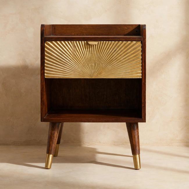 Bedside table with brass-plated drawer and pull-out handle next to a bed