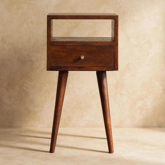 Chestnut-finish mango wood bedside table with one drawer and Nordic-style legs beside a bed